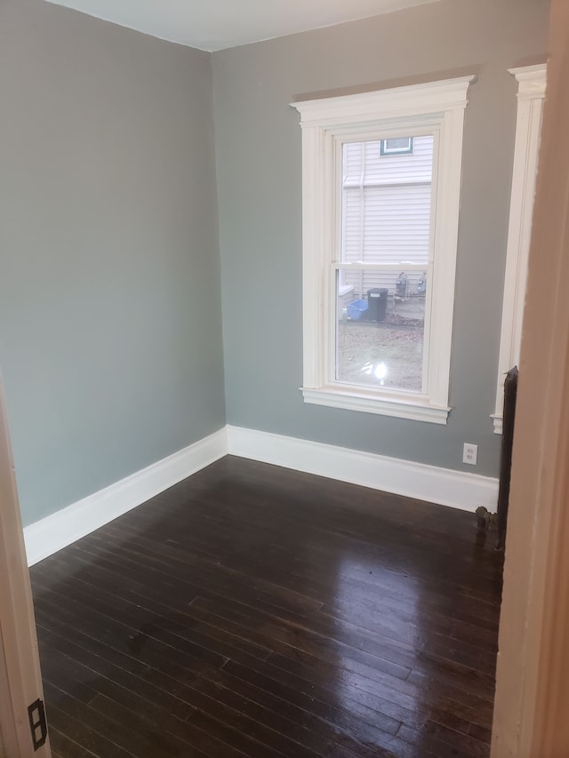 unfurnished room with baseboards and dark wood-style flooring