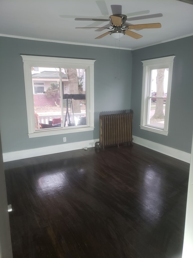 spare room with wood finished floors, radiator, crown molding, baseboards, and ceiling fan