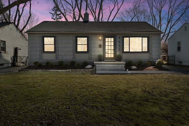 ranch-style home with a lawn and roof with shingles