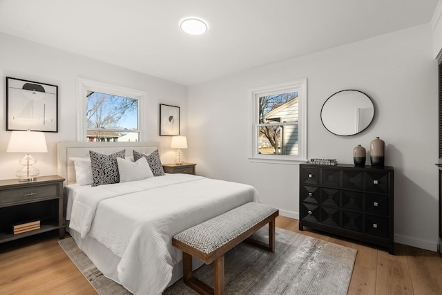 bedroom featuring baseboards, multiple windows, and light wood-style flooring