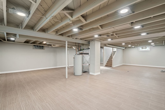 basement featuring water heater, stairway, baseboards, and wood finished floors