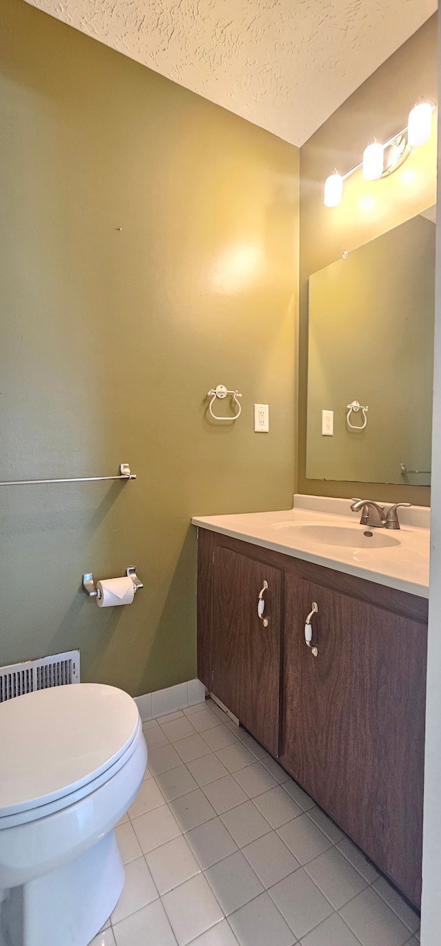 bathroom with vanity, baseboards, tile patterned flooring, a textured ceiling, and toilet