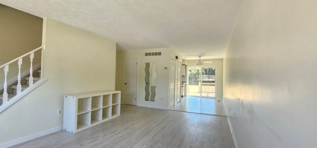 unfurnished room featuring stairs, wood finished floors, visible vents, and baseboards