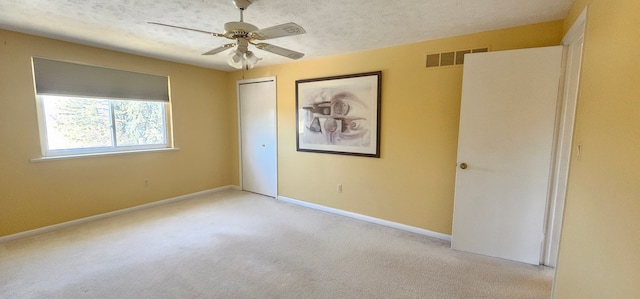 carpeted spare room with ceiling fan, baseboards, visible vents, and a textured ceiling