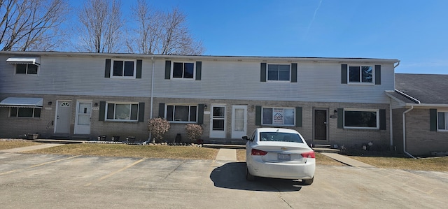 multi unit property featuring entry steps, uncovered parking, and brick siding