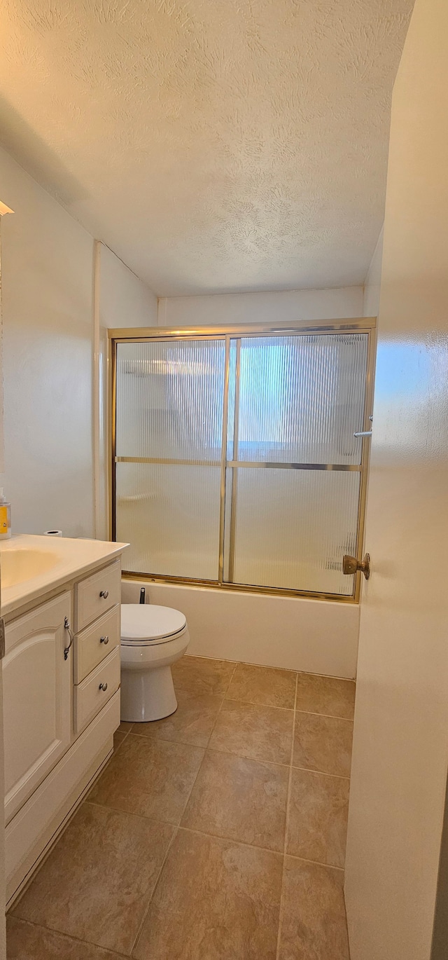 full bathroom with vanity, toilet, bath / shower combo with glass door, and a textured ceiling