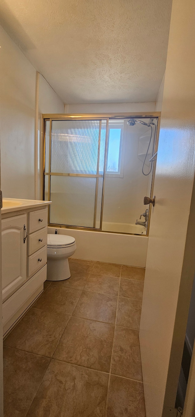 bathroom featuring a textured ceiling, toilet, vanity, and bath / shower combo with glass door