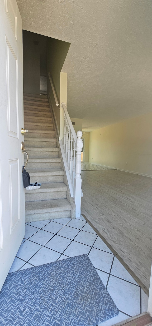 stairs with tile patterned floors and a textured ceiling