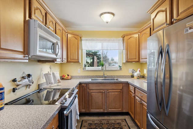 kitchen with a sink, appliances with stainless steel finishes, ornamental molding, and brown cabinetry