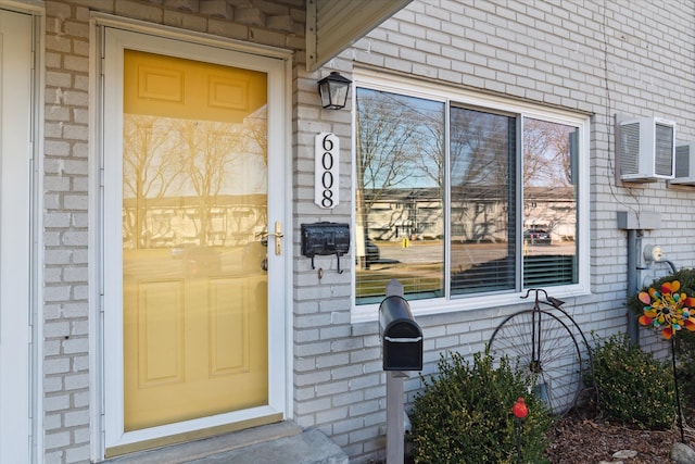 entrance to property with an AC wall unit and brick siding