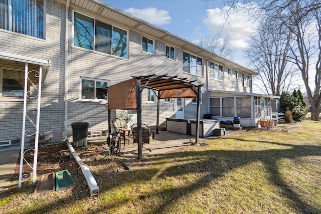 back of house with a lawn, a pergola, a sunroom, brick siding, and a patio area