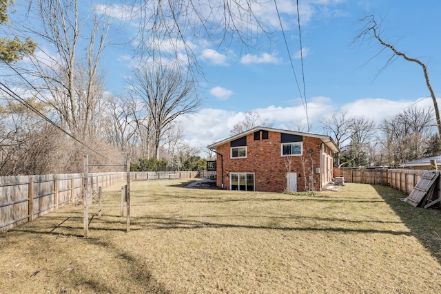 exterior space featuring brick siding, a fenced backyard, and a yard