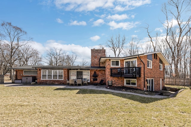 back of house with brick siding, a chimney, and a yard