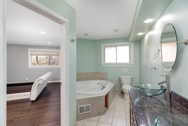 full bath featuring a wealth of natural light, visible vents, a whirlpool tub, and a sink