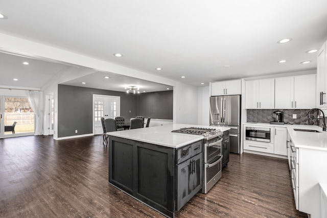 kitchen with dark wood finished floors, open floor plan, light countertops, appliances with stainless steel finishes, and a sink