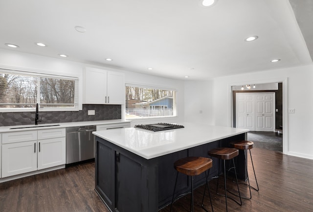 kitchen with a sink, dishwasher, decorative backsplash, white cabinets, and dark wood-style flooring