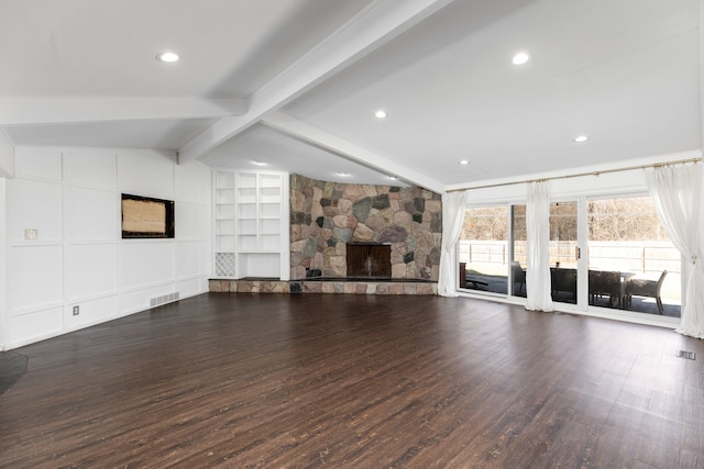 unfurnished living room featuring visible vents, built in shelves, lofted ceiling with beams, dark wood finished floors, and a stone fireplace