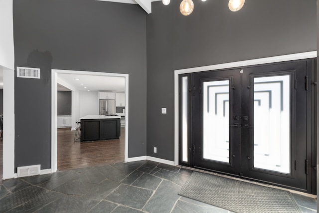 foyer with french doors, visible vents, a towering ceiling, and baseboards