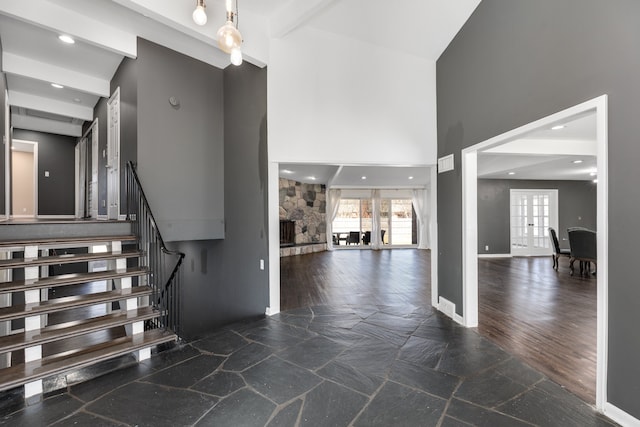 interior space featuring stone tile floors, french doors, a high ceiling, a fireplace, and baseboards