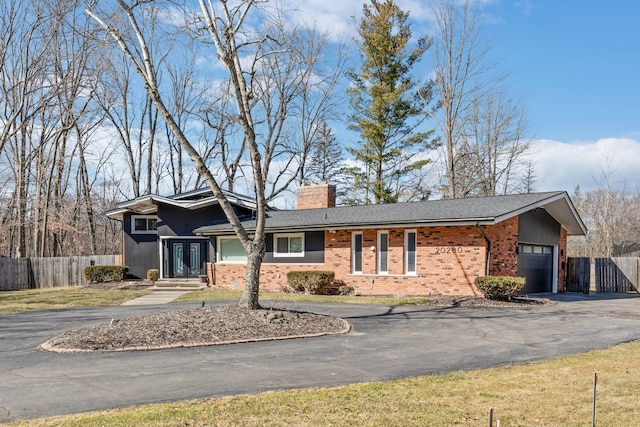 ranch-style house featuring brick siding, driveway, a chimney, and fence