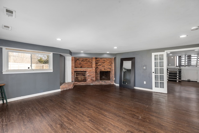 unfurnished living room featuring visible vents, a healthy amount of sunlight, wood finished floors, and a fireplace