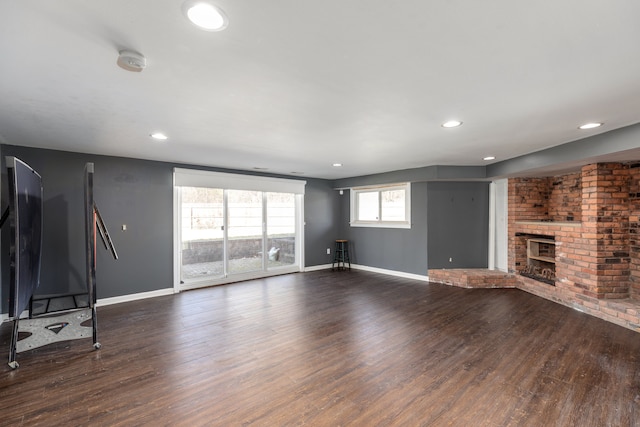 unfurnished living room with recessed lighting, a fireplace, dark wood-style flooring, and baseboards