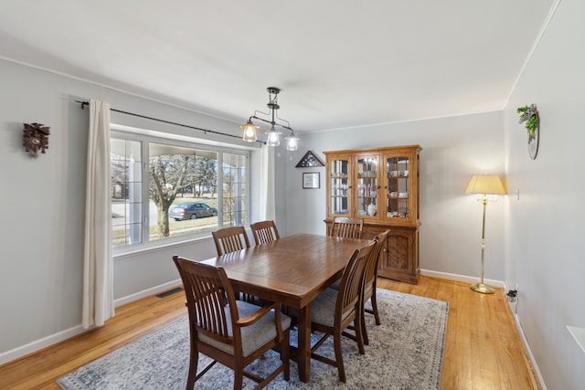 dining area featuring visible vents, light wood-style flooring, and baseboards