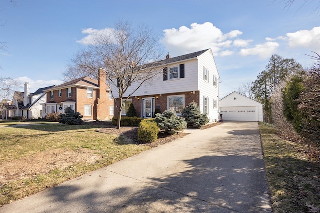 colonial-style house featuring a front yard, a chimney, an outdoor structure, a detached garage, and brick siding