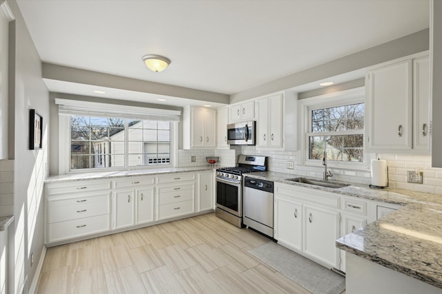 kitchen featuring white cabinetry, backsplash, appliances with stainless steel finishes, and a sink