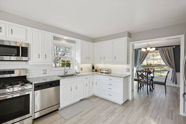 kitchen featuring a notable chandelier, white cabinets, appliances with stainless steel finishes, and a sink