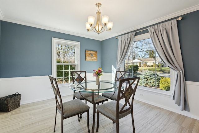 dining area featuring a wealth of natural light, a wainscoted wall, a notable chandelier, and ornamental molding