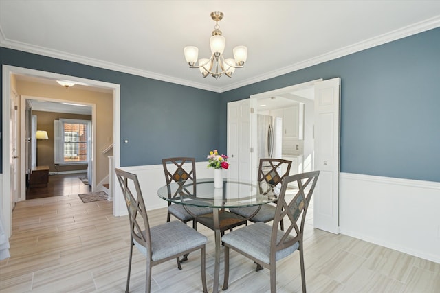 dining area featuring an inviting chandelier, wainscoting, light wood finished floors, and ornamental molding