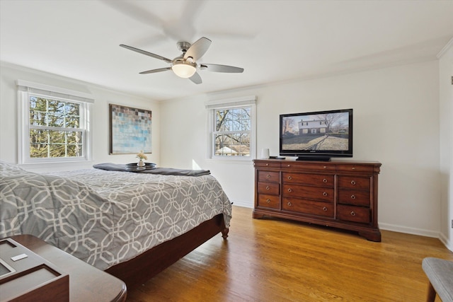 bedroom with baseboards, a ceiling fan, light wood-style flooring, and crown molding