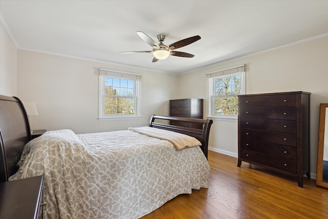 bedroom with multiple windows, wood finished floors, baseboards, and ornamental molding