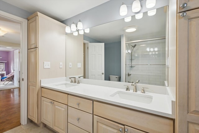 bathroom with a sink, toilet, a stall shower, and double vanity