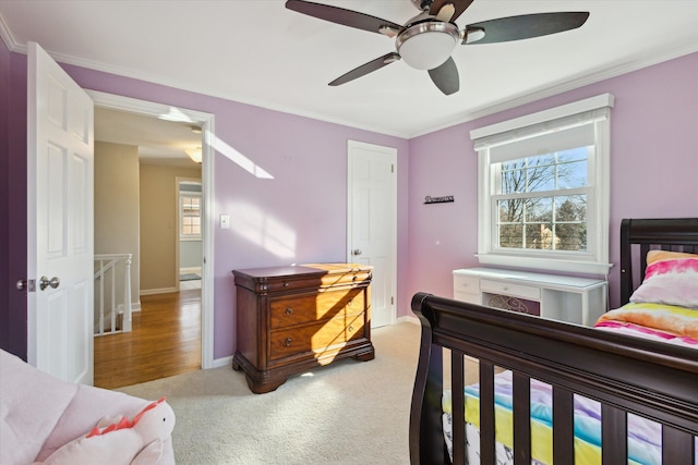 bedroom with ceiling fan, crown molding, baseboards, and light carpet