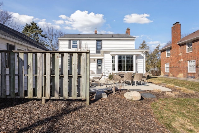 back of property featuring a patio area, fence, and a chimney