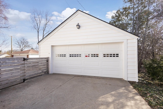 detached garage featuring driveway and fence