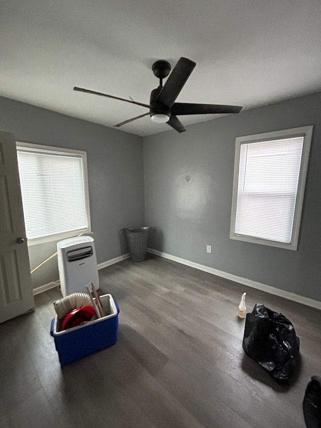 interior space featuring a ceiling fan, baseboards, and wood finished floors