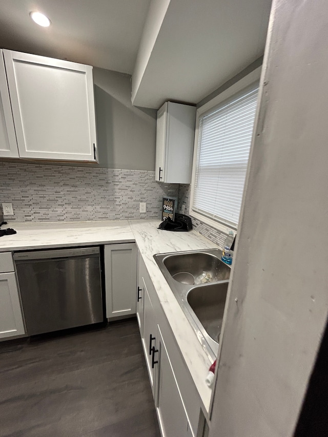 kitchen with tasteful backsplash, dishwasher, light stone counters, dark wood-style floors, and a sink