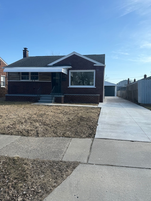 view of front of home with brick siding, fence, a porch, an outdoor structure, and driveway