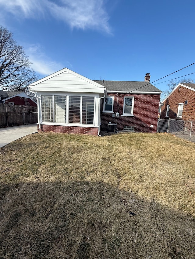 rear view of property featuring central air condition unit, a yard, fence, and brick siding