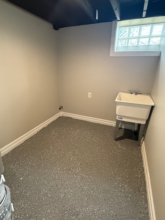 basement with baseboards and a sink