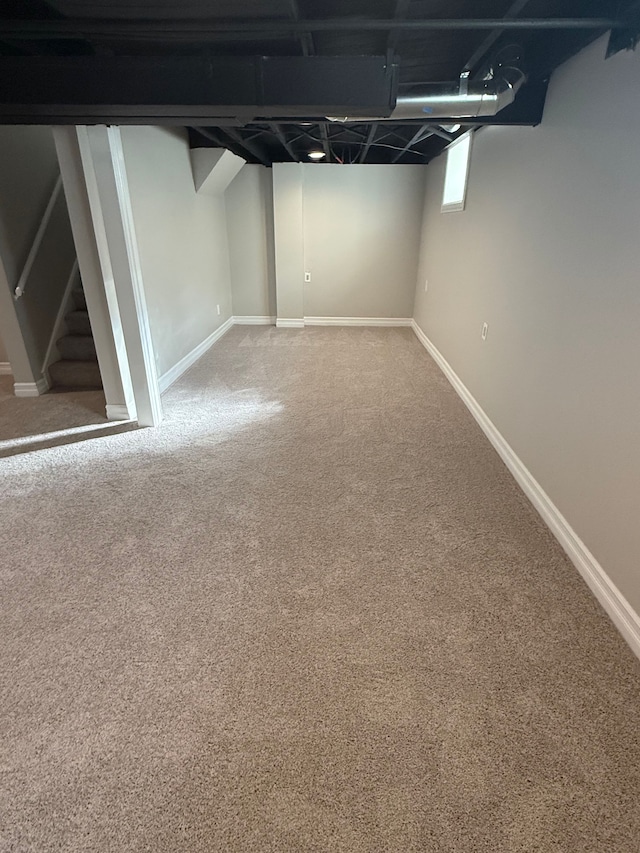 basement featuring baseboards, carpet, and stairs