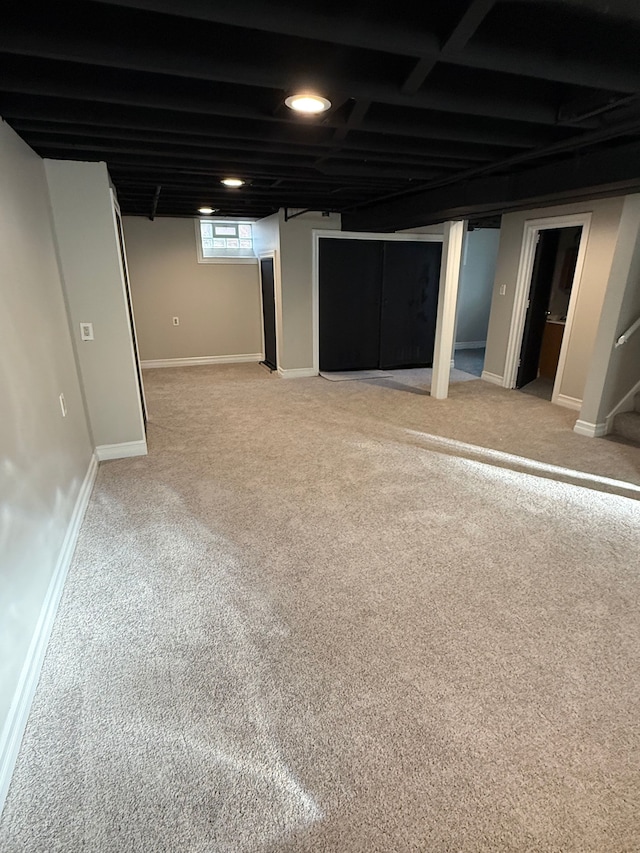 below grade area with stairway, light carpet, and baseboards