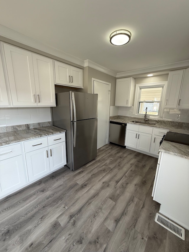 kitchen featuring white cabinets, stainless steel appliances, crown molding, and a sink