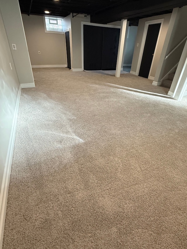 below grade area featuring stairs, baseboards, and carpet floors