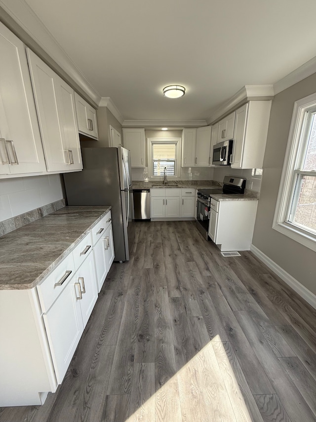 kitchen featuring visible vents, ornamental molding, appliances with stainless steel finishes, dark wood-style floors, and white cabinets