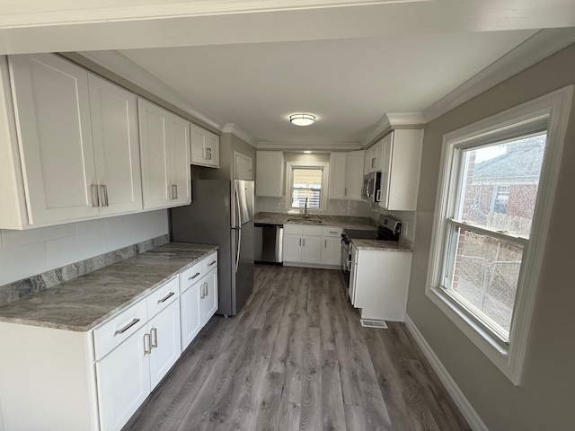 kitchen featuring visible vents, ornamental molding, appliances with stainless steel finishes, and a sink