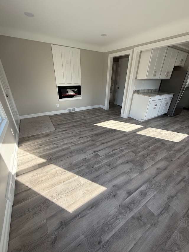 unfurnished living room with visible vents, baseboards, dark wood finished floors, and a fireplace